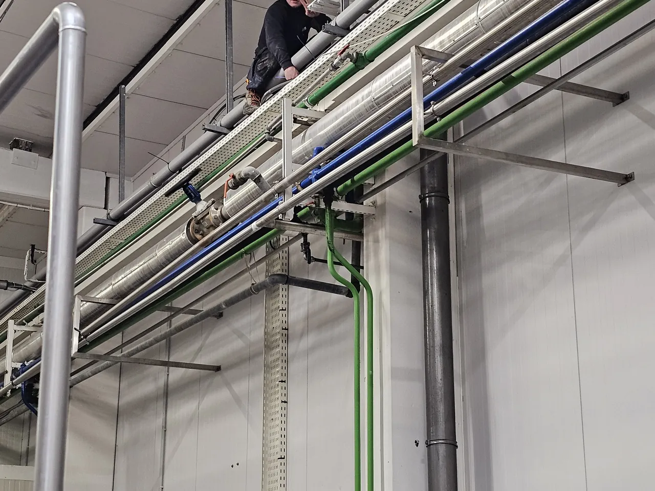 Technicien Ets Coekaerts posant des chemins de câbles en site industriel
